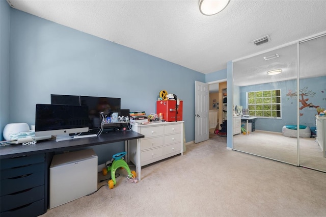 office with visible vents, light carpet, and a textured ceiling