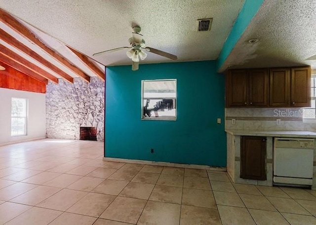 kitchen featuring dishwasher, a textured ceiling, vaulted ceiling with beams, and light tile patterned flooring