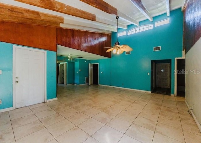 kitchen featuring beam ceiling, ceiling fan, light tile patterned floors, and a high ceiling