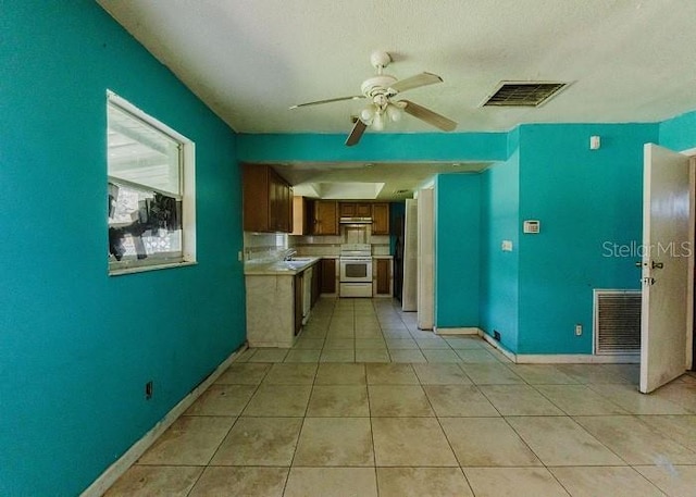 kitchen with ceiling fan, sink, light tile patterned floors, and white range