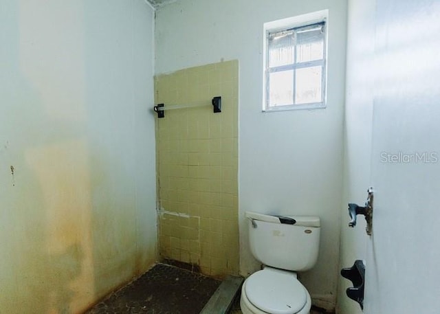 bathroom featuring tiled shower and toilet