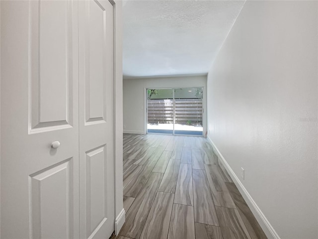 corridor featuring light hardwood / wood-style floors and a textured ceiling