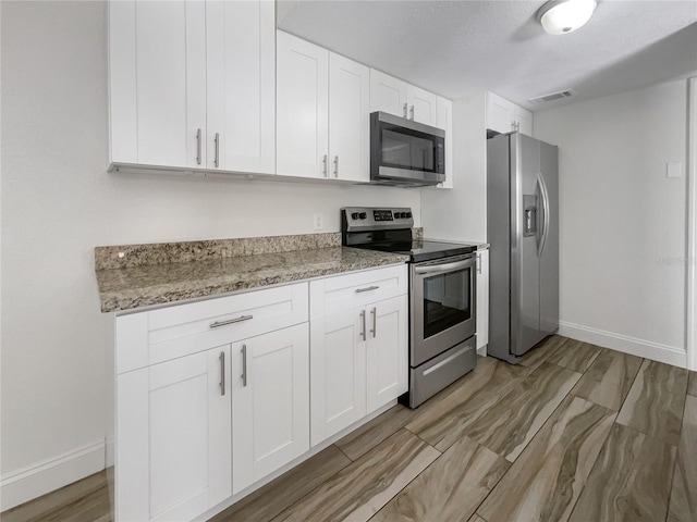 kitchen with light stone counters, white cabinets, and appliances with stainless steel finishes