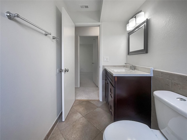 bathroom with tile patterned floors, tile walls, toilet, and vanity