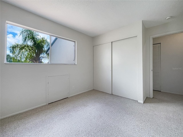 unfurnished bedroom featuring a textured ceiling, a closet, and light carpet