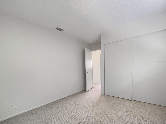 interior space with a closet, a textured ceiling, and light carpet