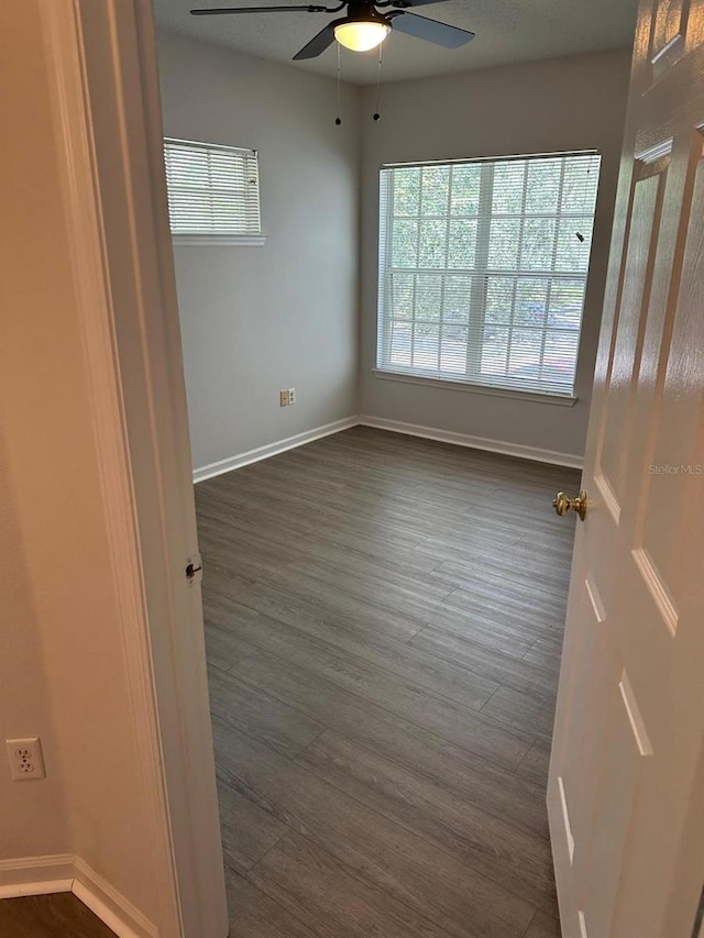 empty room with dark hardwood / wood-style floors and ceiling fan