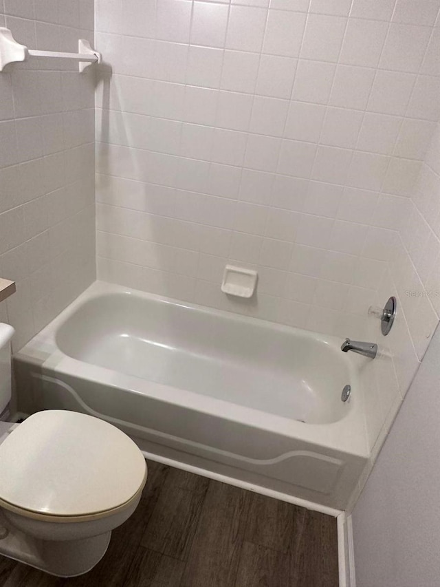 bathroom featuring tiled shower / bath combo, toilet, and wood-type flooring