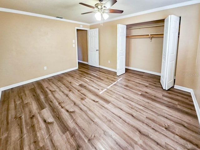 unfurnished bedroom featuring crown molding, light hardwood / wood-style flooring, a closet, and ceiling fan