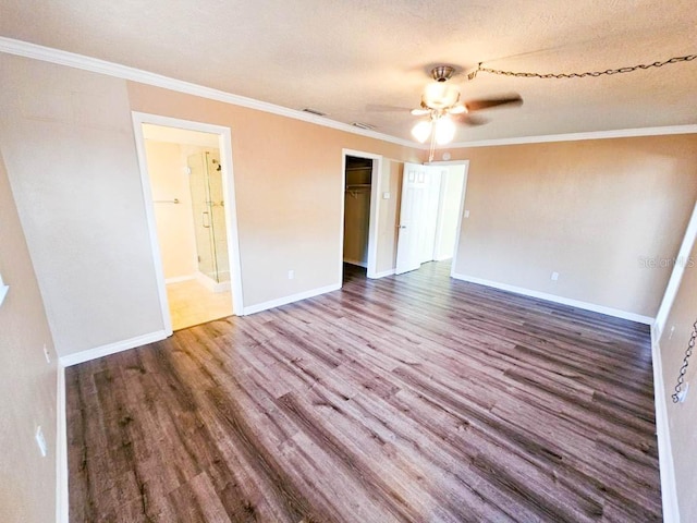 unfurnished bedroom featuring a spacious closet, hardwood / wood-style floors, ensuite bath, a closet, and ornamental molding