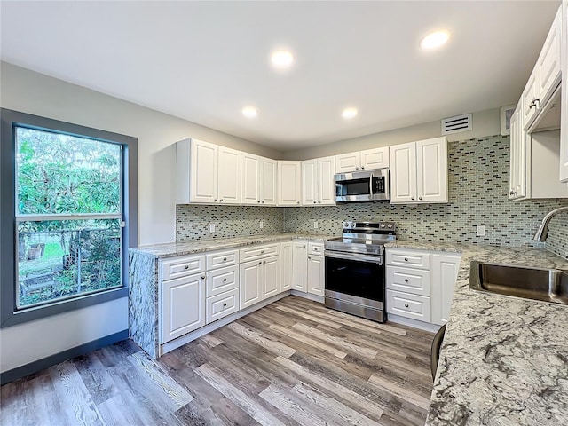 kitchen with sink, hardwood / wood-style floors, backsplash, and stainless steel appliances