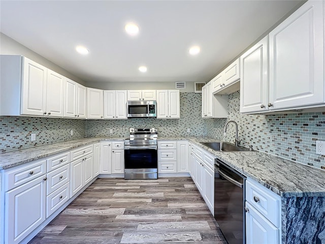 kitchen featuring sink, white cabinetry, light wood-type flooring, stainless steel appliances, and light stone countertops