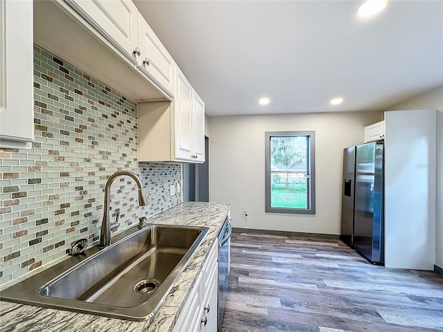 kitchen featuring hardwood / wood-style flooring, tasteful backsplash, white cabinets, stainless steel fridge with ice dispenser, and sink