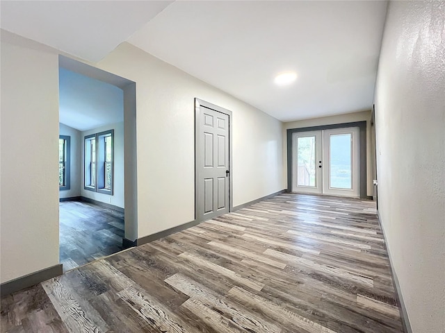 empty room featuring wood-type flooring, french doors, and a healthy amount of sunlight