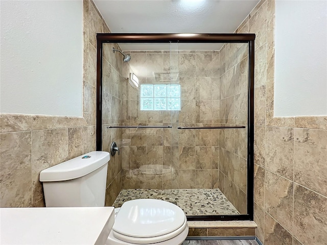 bathroom with an enclosed shower, tile walls, and toilet