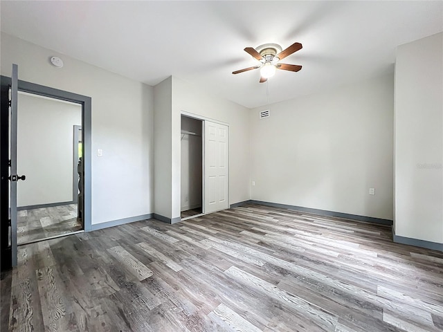 unfurnished bedroom featuring hardwood / wood-style flooring, a closet, and ceiling fan