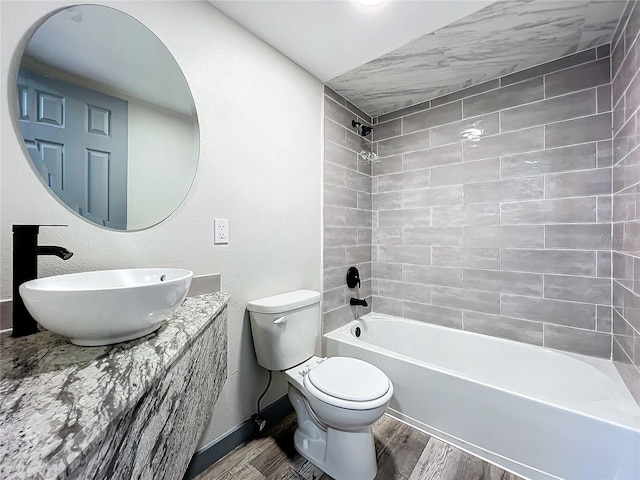 full bathroom with hardwood / wood-style flooring, toilet, tiled shower / bath combo, and vanity