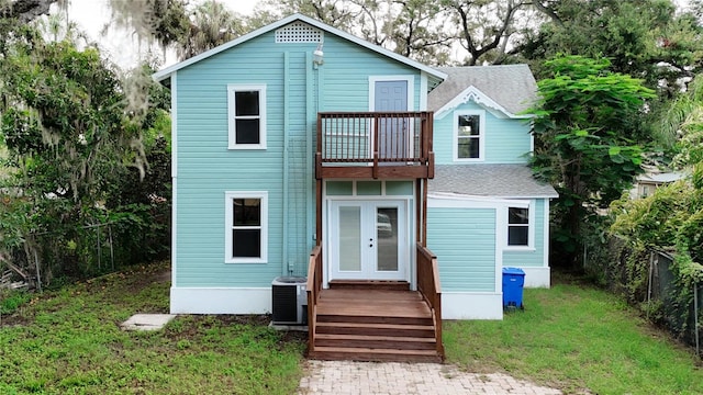 view of front of house with a balcony, central AC, and a front lawn