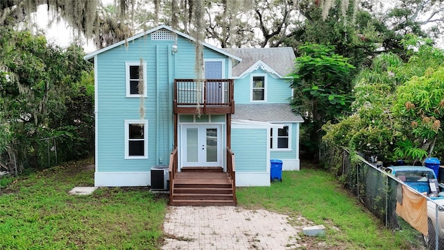 view of front of house with a balcony, central AC, and a front yard