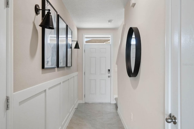 hall featuring light tile patterned floors and a textured ceiling