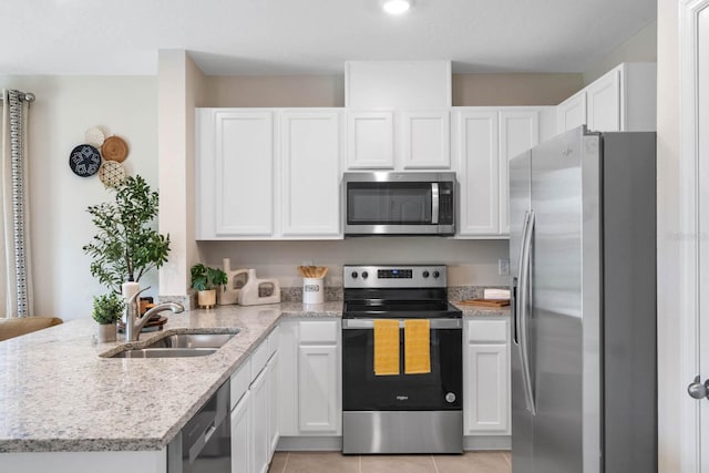 kitchen with white cabinetry, sink, light stone countertops, appliances with stainless steel finishes, and light tile patterned floors