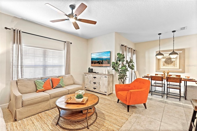 tiled living room featuring ceiling fan and a textured ceiling