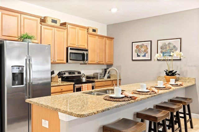 kitchen featuring stainless steel appliances, light stone countertops, sink, and light brown cabinetry