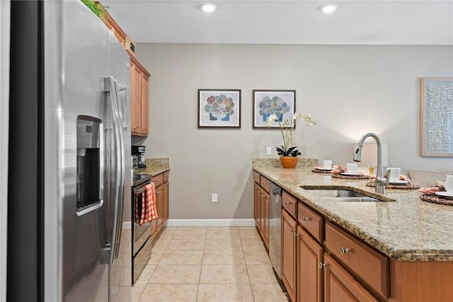 kitchen with sink, light tile patterned floors, appliances with stainless steel finishes, light stone counters, and kitchen peninsula