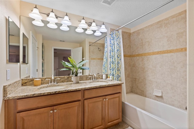 bathroom with vanity, shower / tub combo with curtain, and a textured ceiling