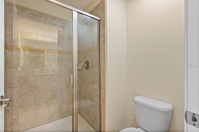 bathroom featuring a shower with shower door and toilet