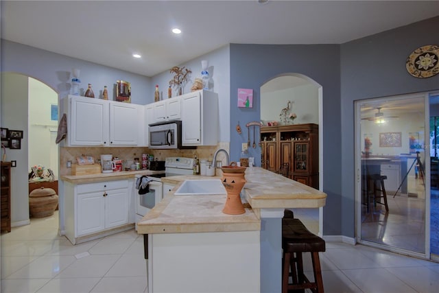 kitchen with white cabinets, light tile patterned flooring, white electric stove, and backsplash