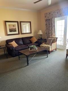 carpeted living room with ceiling fan and crown molding