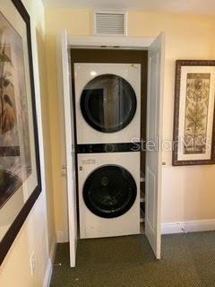 washroom with stacked washer and clothes dryer and dark colored carpet