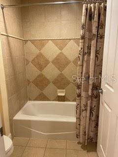 bathroom featuring shower / tub combo with curtain, toilet, and tile patterned floors