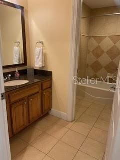 bathroom featuring tile patterned flooring, vanity, and tiled shower / bath