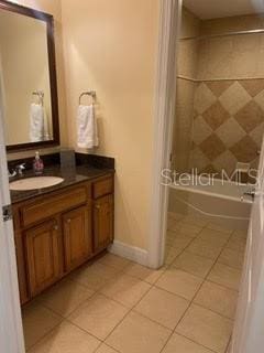 full bath featuring baseboards, bathing tub / shower combination, vanity, and tile patterned floors