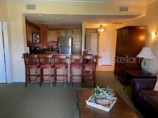 kitchen featuring appliances with stainless steel finishes, carpet flooring, a kitchen bar, and crown molding