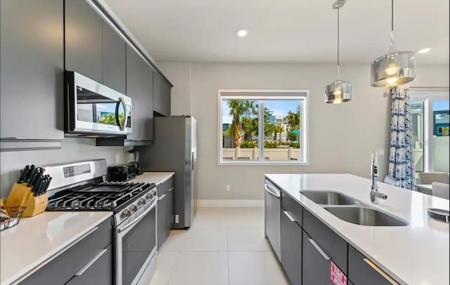 kitchen with sink, hanging light fixtures, light tile patterned floors, and appliances with stainless steel finishes