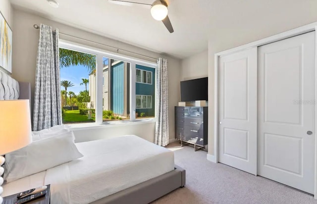 bedroom featuring a closet, ceiling fan, light colored carpet, and multiple windows