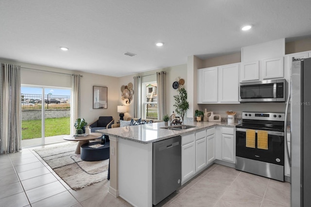 kitchen featuring stainless steel appliances, sink, light stone counters, kitchen peninsula, and light tile patterned flooring