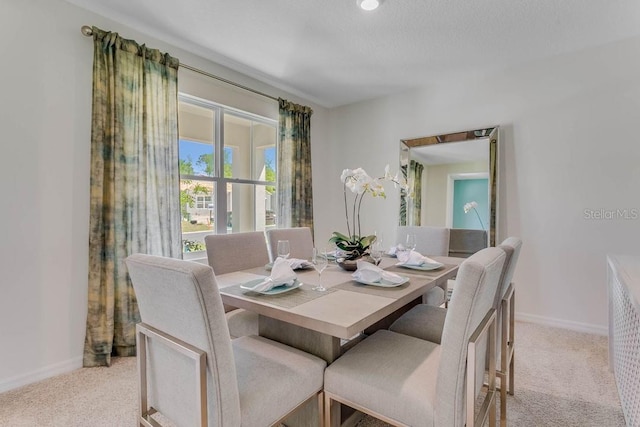 dining space featuring light carpet and a textured ceiling