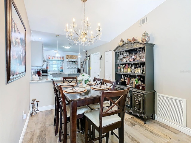 dining room featuring a notable chandelier, light hardwood / wood-style floors, and sink