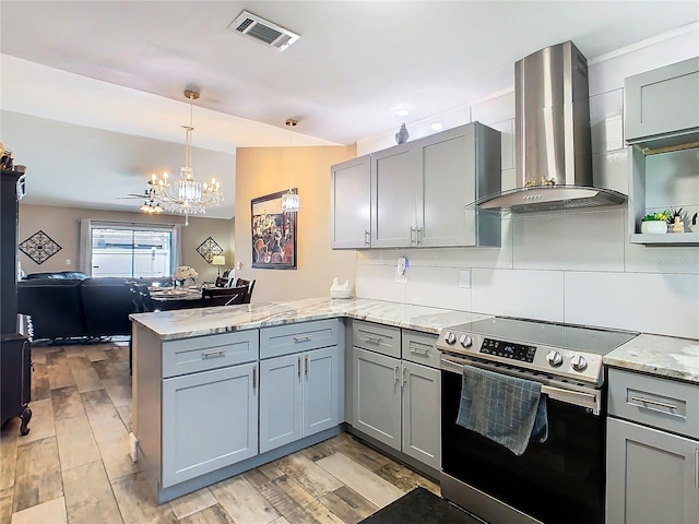 kitchen with stainless steel electric range, hanging light fixtures, wall chimney exhaust hood, tasteful backsplash, and kitchen peninsula