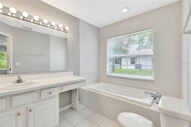 bathroom with tile patterned floors, vanity, tiled bath, and toilet