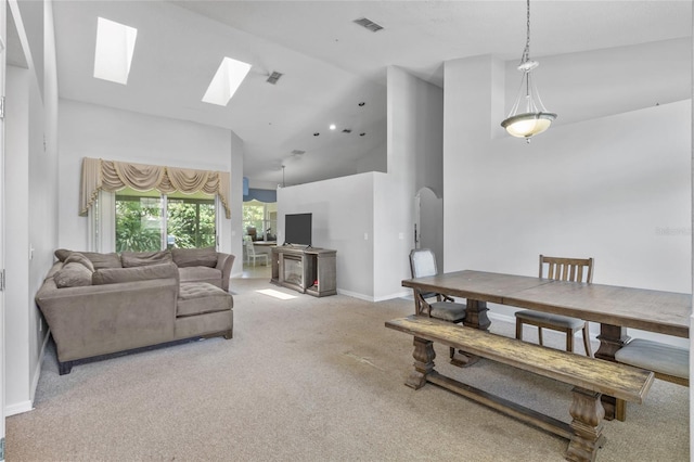 carpeted living room featuring high vaulted ceiling and a skylight