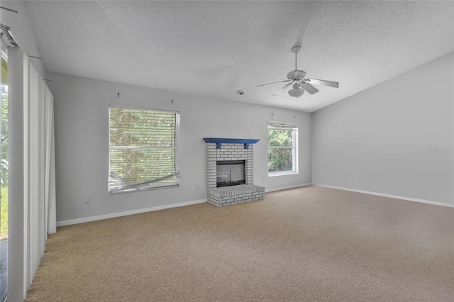 unfurnished living room with ceiling fan, light colored carpet, a textured ceiling, and a brick fireplace