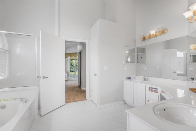 bathroom with independent shower and bath, a towering ceiling, and vanity