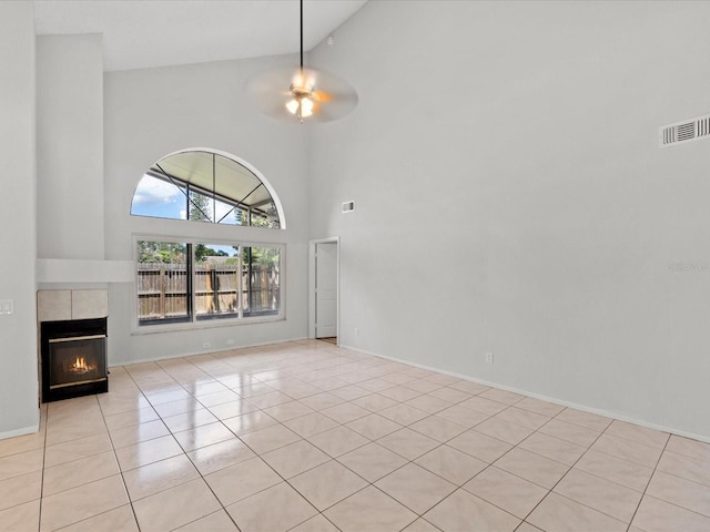 unfurnished living room featuring a fireplace, high vaulted ceiling, ceiling fan, and light tile patterned flooring