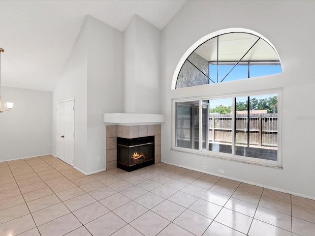 unfurnished living room featuring a notable chandelier, a tile fireplace, and high vaulted ceiling