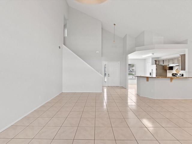 unfurnished living room with high vaulted ceiling and light tile patterned floors